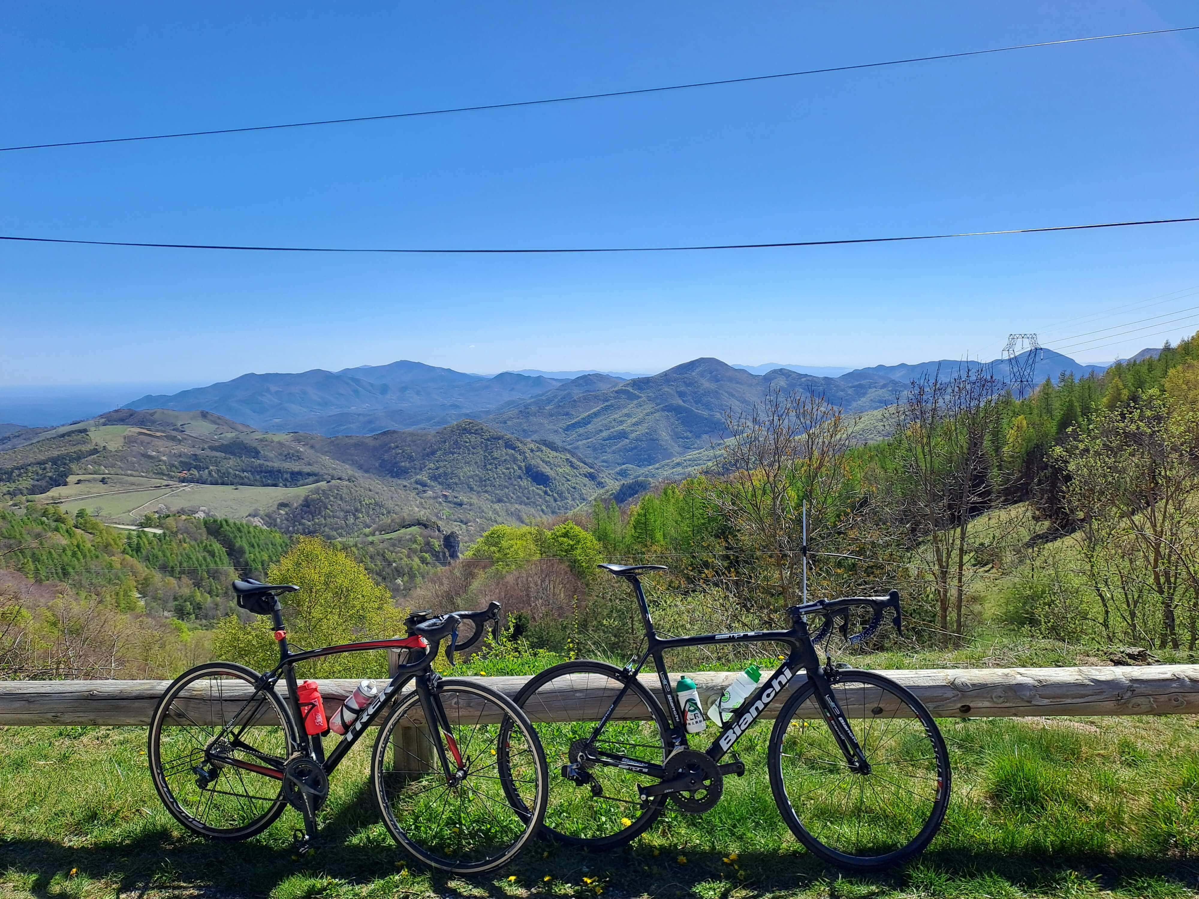 Dos bicicletas apoyadas en una valla frente a un panorama montañoso iluminado por la luz del día